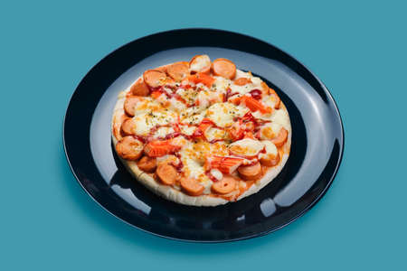 Sausage and Crab Stick Pizza in a ceramic plate isolated on pastel colors background.の写真素材