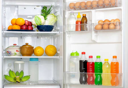 Look into the refrigerator with the lid open a lots of fresh food and drinks inside.の写真素材