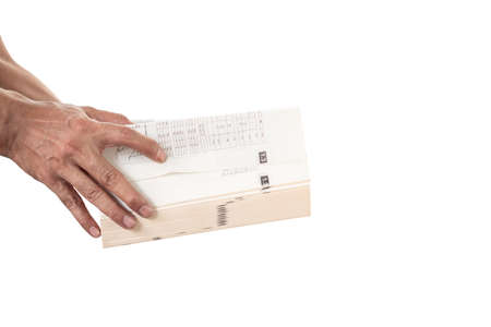 Close-up of man's hand holding and opening a thick book on white background.の写真素材