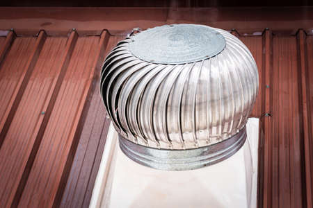 Closeup a ventilation chimney on the roof that relies on wind to rotate.