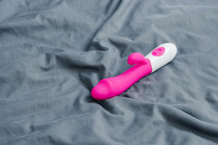 Close-up of vibrating sex toy lying on crumpled mattress.の写真素材