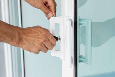 Close-up of man's hand opening a glass door with a key.の写真素材