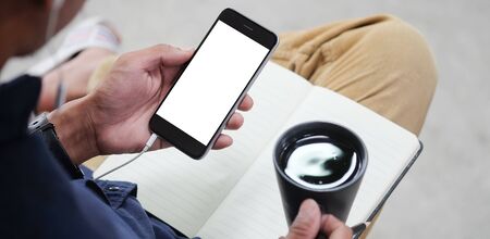 Cropped shot view of man hands holding smart phone with blank copy space screen for your text message or information content, female reading text message on cell telephone during in urban setting. の写真素材