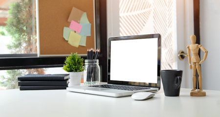 Cropped shot of modern workspace with blank screen laptop on white table.の写真素材
