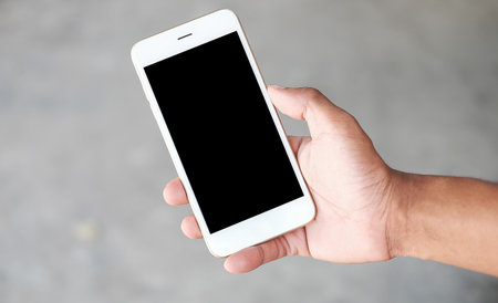 Cropped shot view of man hands holding smart phone with blank copy space screen for your text message or information content, female reading text message on cell telephone during in urban setting.の写真素材