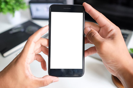 Mock up smartphone of hand holding black mobile phone with blank white screen.の写真素材