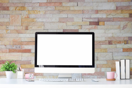 Work place with blank screen computer pc and office supplies on white table with brick wall in vintage office.の写真素材
