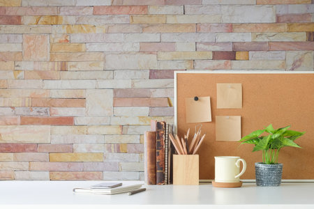 Copyspace of office equipment on white table with stone wall texture background.