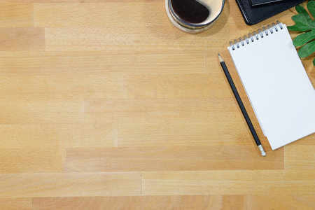 Top view of blank screen smart phone on wooden office desk with coffee cup, keyboard, supplies and copy space.の写真素材