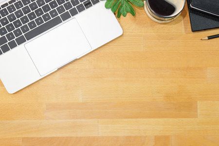 Top view of blank screen smart phone on wooden office desk with coffee cup, keyboard, supplies and copy space.の写真素材