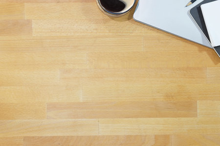 Top view of blank screen smart phone on wooden office desk with coffee cup, keyboard, supplies and copy space.の写真素材