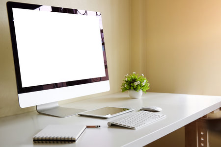 Minimal work space with mock up computer with white screen, coffee cup and office supplies on white...