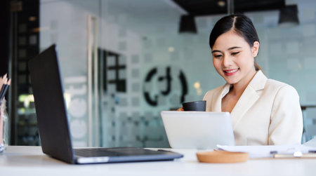 Experienced businesswoman reading publication via laptop computer making research for planning startup at desktop in modern office.の写真素材