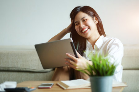 Woman relaxing on sofa in the living room enjoying sunny morning on the day Happy casual beautiful woman working on a laptop sitting in the house.の写真素材