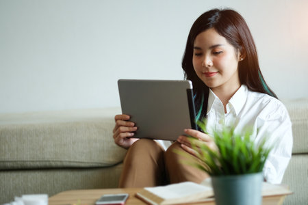 Portrait of young female designer is sitting at graphic studio in front of laptop computer while working online.の写真素材