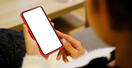 Close up view of young woman hands holding mock up smart phone with blank white screen at her...