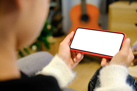 Close up view of young woman hands holding mock up smart phone with blank white screen at her...