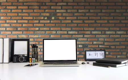 Simple workspace with computer, equipment and brick wall background.の写真素材