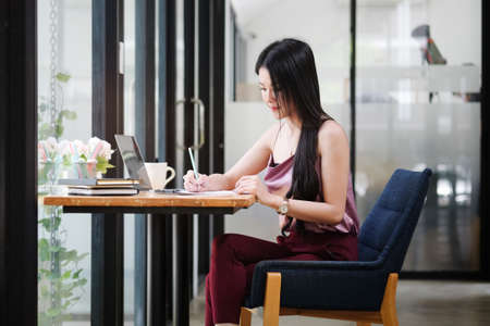 Experienced businesswoman reading publication via laptop computer making research for planning startup at desktop in modern office.の写真素材