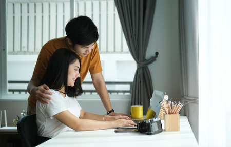 Young couple are relaxing on comfortable couch while looking at digital tablet screen in living room at home.の写真素材