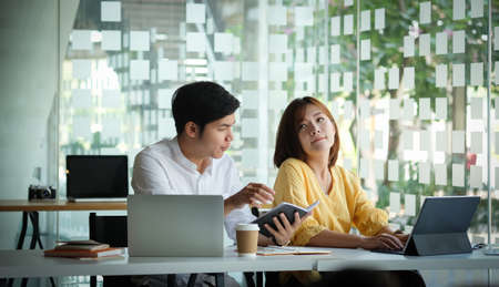 Two businesspeople preparing their project with digital device in modern office.の写真素材