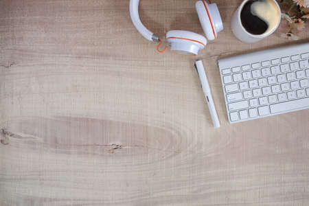 Top view of blank screen smart phone on wooden office desk with coffee cup, keyboard, supplies and copy space.の写真素材