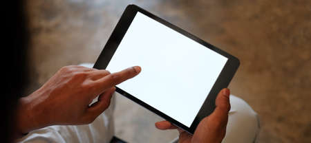 Close up of business man handing hold tablet with white screen  on office desk.