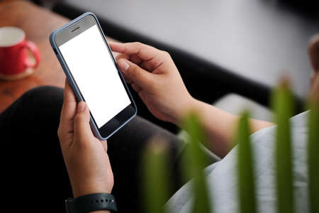 Mock up smartphone of hand holding black mobile phone with blank white screen.