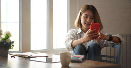 Side view businesswoman using mobile phone at office desk.の写真素材