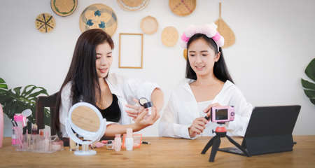 Two young beauty blogger woman recording vlog video with makeup cosmetic at home.