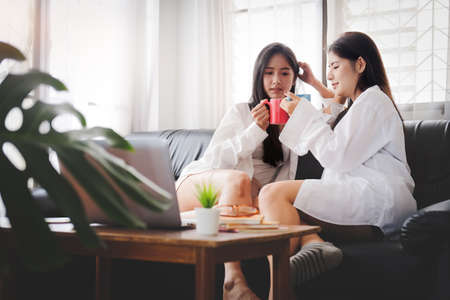 Lesbian women couple relaxing together on sofa in living room. LGBT concept.の写真素材