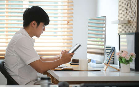 Business woman reading information on paperwork and using laptop working on desk.
