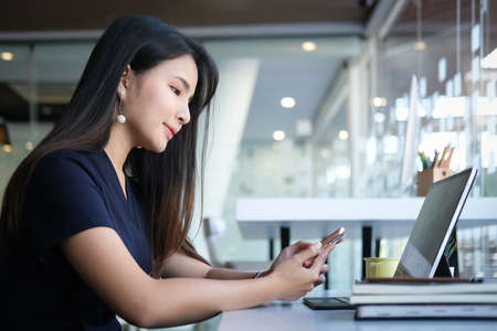 Side view of businesswoman using smartphone browsing and messaging with friends.の写真素材