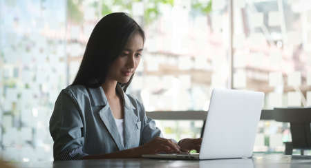 A businesswoman working on new project with laptop computer in modern office.の写真素材