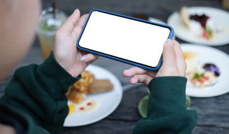 Mock up smartphone of hand holding black mobile phone with blank white screen.