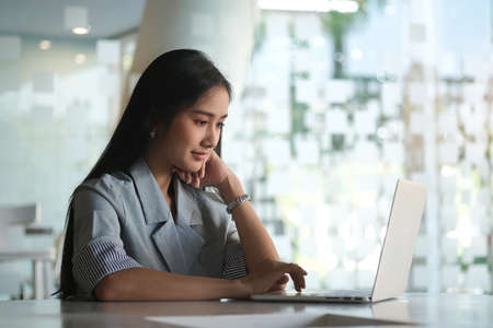 A businesswoman working on new project with laptop computer in modern office.の写真素材
