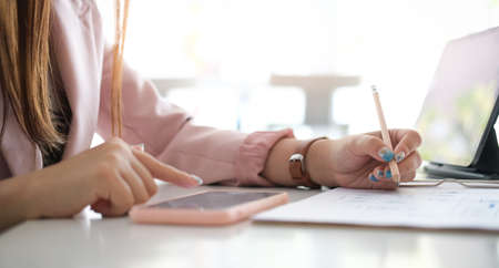 Cropped shot of office workers checking statistics on paper documents and working on tablet computer...