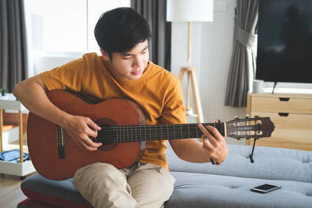 Happy young couple sitting relax on sofa in living room and have fun browse internet on tablet at home on weekend.の写真素材