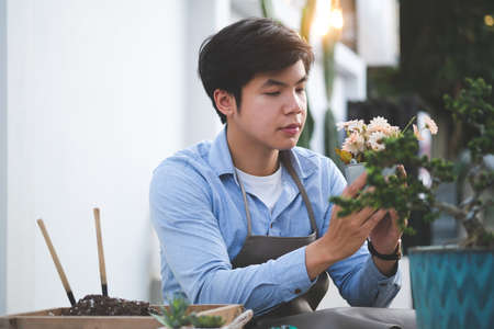 Cropped shot of man trimming florist ties a rope to arrange modern bouquet