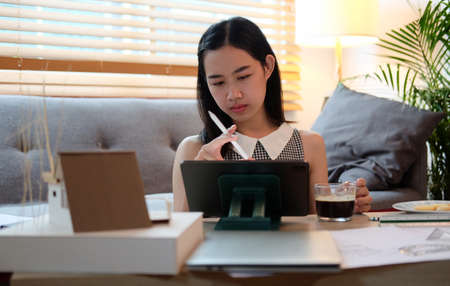 Female architect working with digital tablet and blueprint at home.