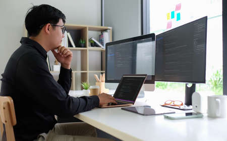 Side view of man programmer working on project in modern office.の写真素材