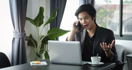 Successful businessman working with laptop and talking on mobile phone.