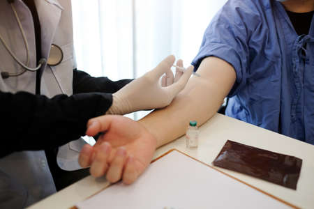 Doctor or nurse giving injection to patient.