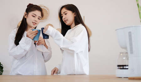Lesbian couple drinking coffee together in the morning at home.