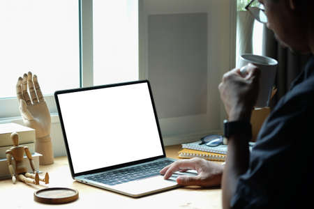 Cropped shot businessman drinking coffee and checking email on laptop computer.