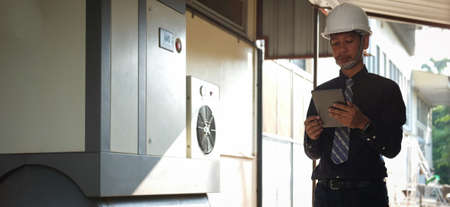 Engineers in safety helmet holding digital tablet while standing in the industrial
