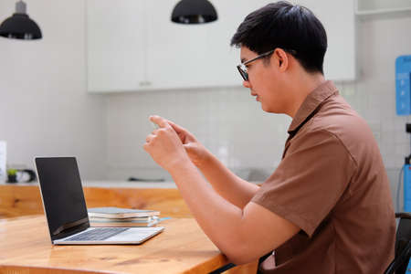 Side view young man sitting in kitchen and using mobile phone.
