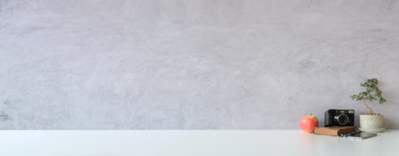 Empty picture frame, houseplant and camera on white table.