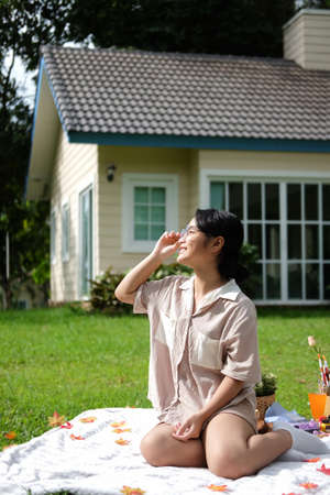 Happy Asian woman sitting in the garden and enjoying the fresh air in sunny day.の写真素材