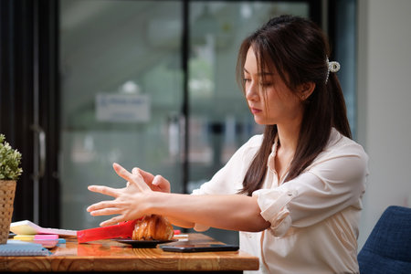 Young Asian woman having breakfast at office.の写真素材